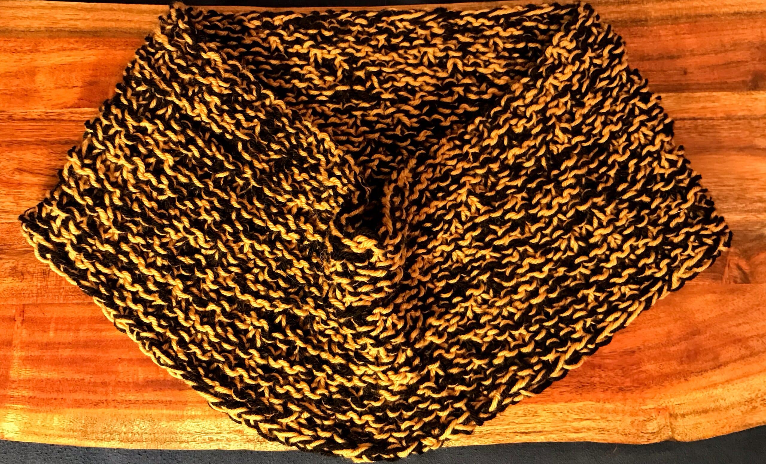 gold and black wool cowl displayed on wood background