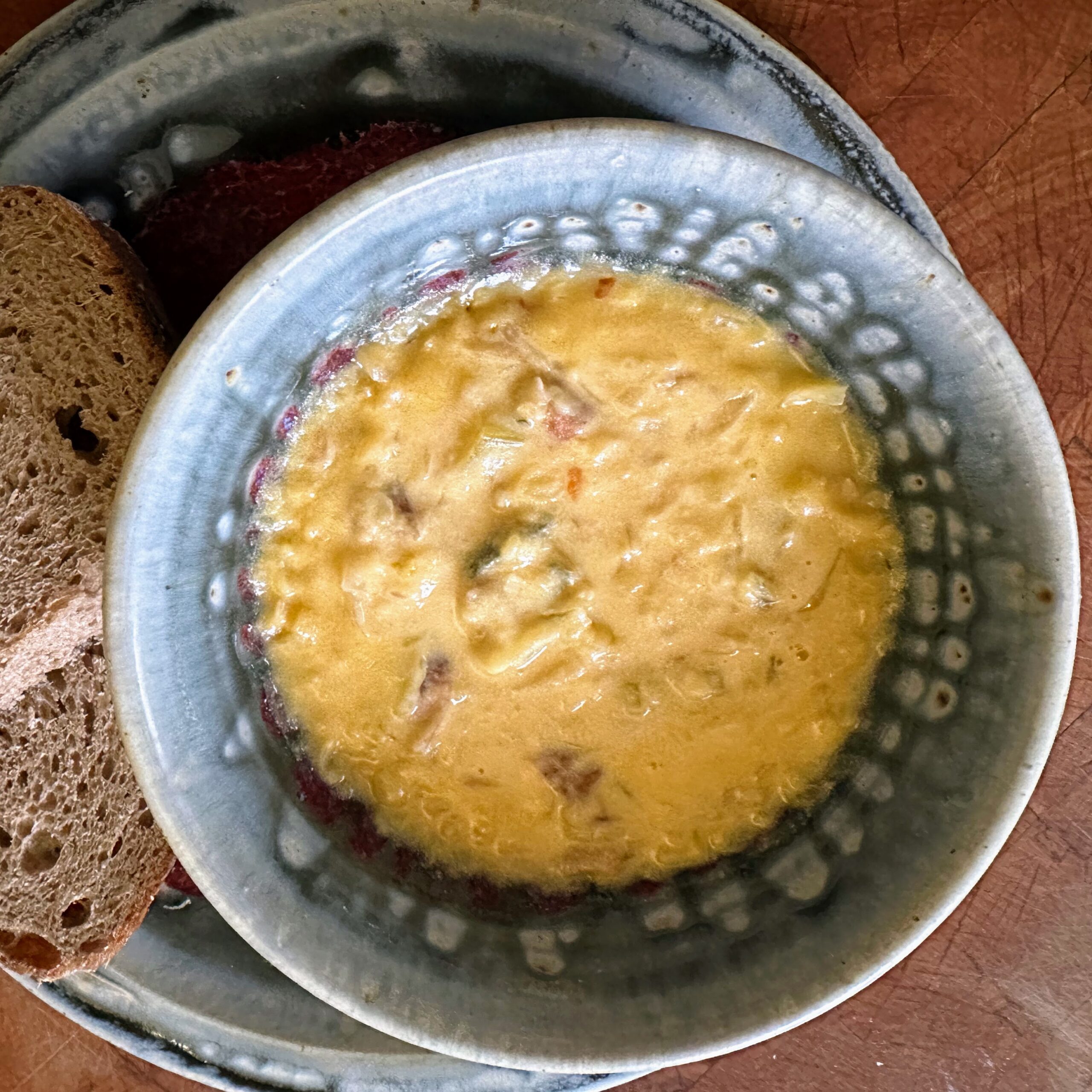 cheesy potato soup in a red and gray bowl