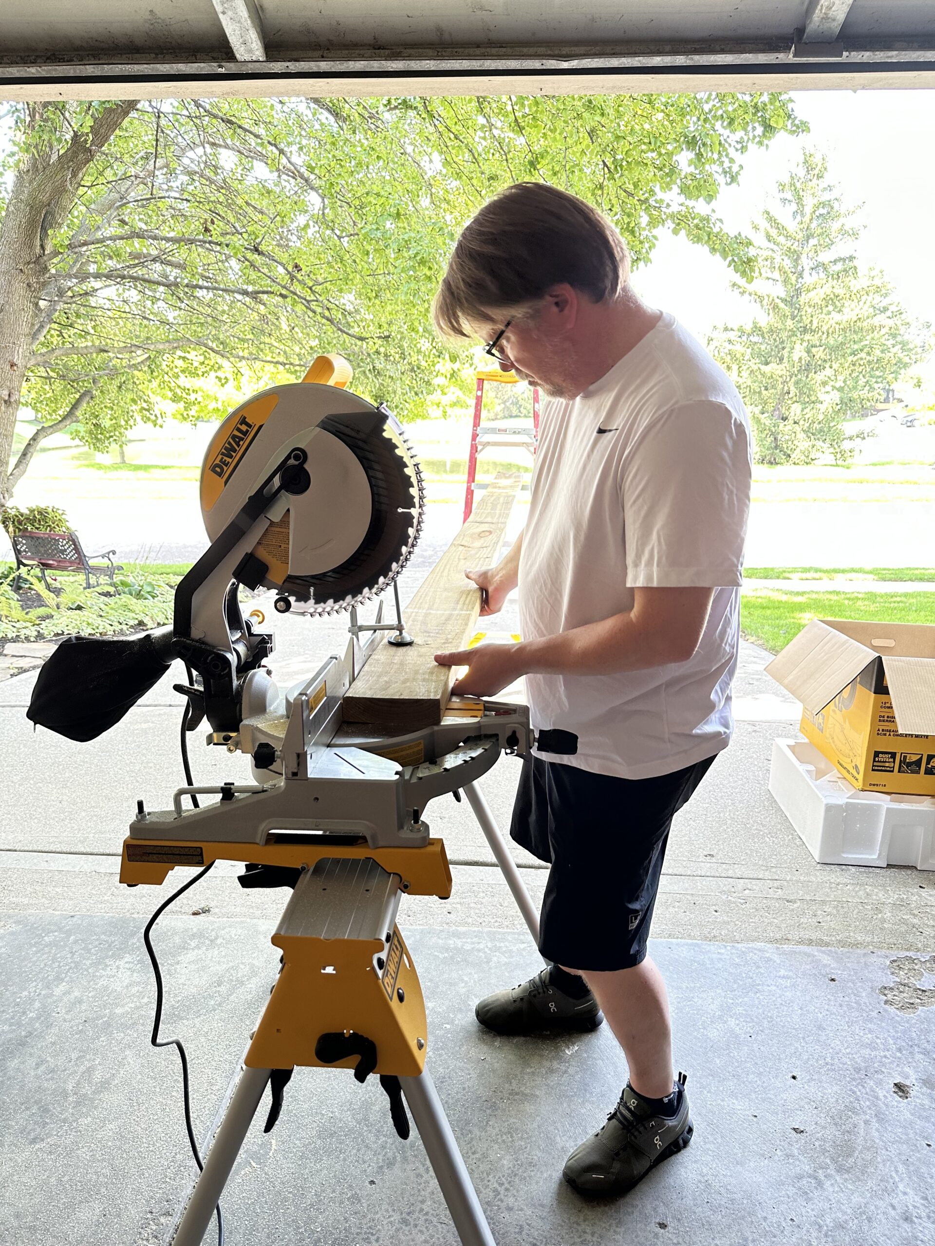 Rich standing at the miter saw measuring a floor joist in the garage