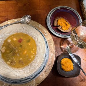 seafood stew in a pottery bowl with a glass of white wine and crusty bread with rouille