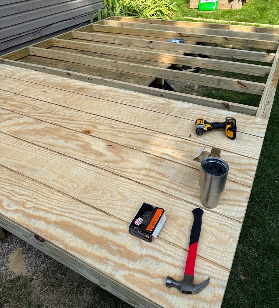 Attaching the first piece of reverse board and batten siding to the back wall