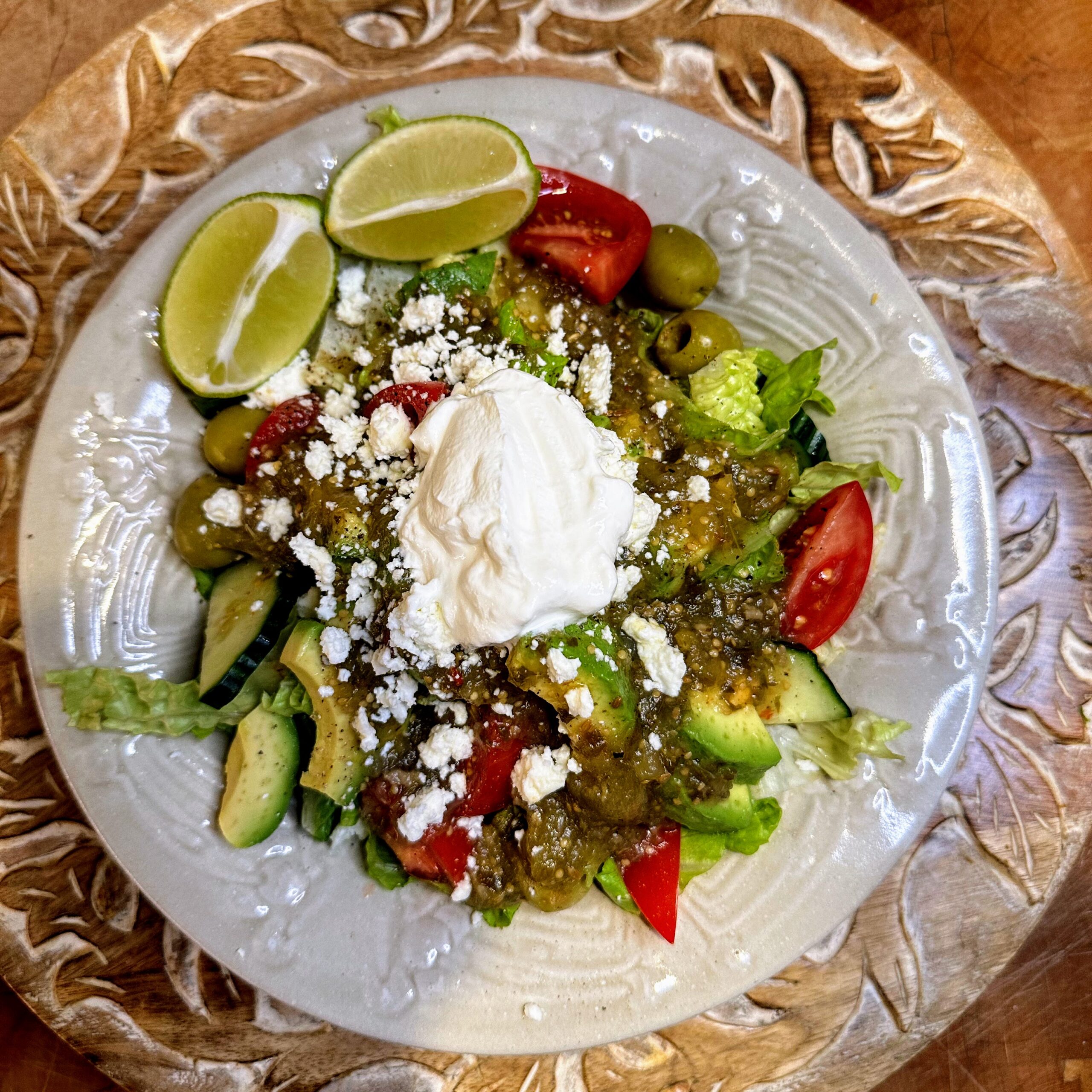 Fajita veggies bowl topped with salsa verde, cojita cheese, and sour cream in a white pottery bowl