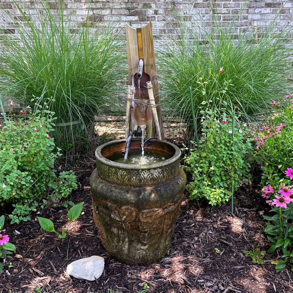 Large urn fountain in a garden with a copper sluice 