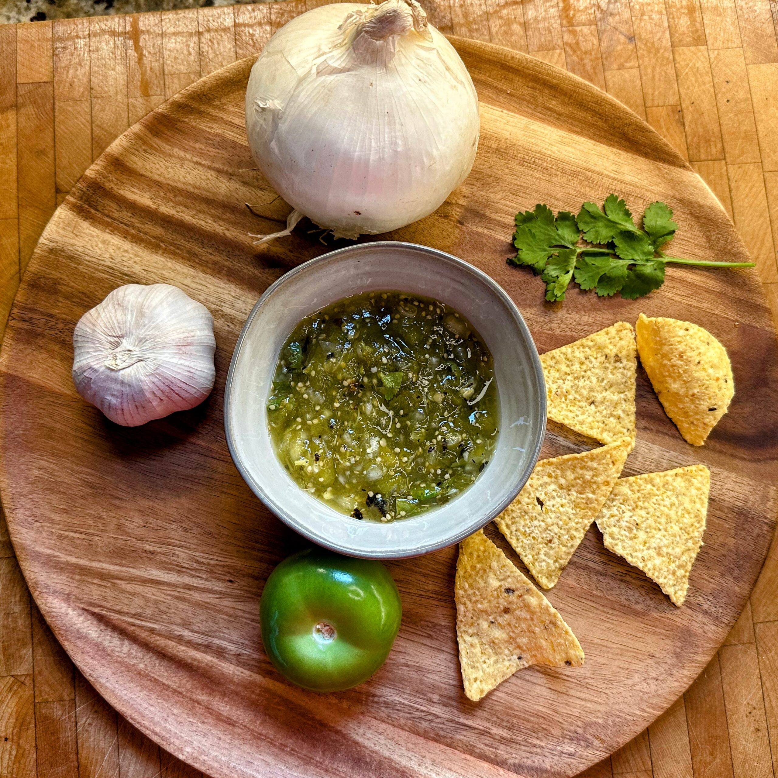 Roasted Fresh Salsa Verde on a wood tray surrounded by veggies